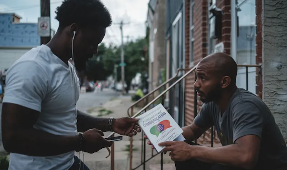 Two men talk on the front steps of a rowhome